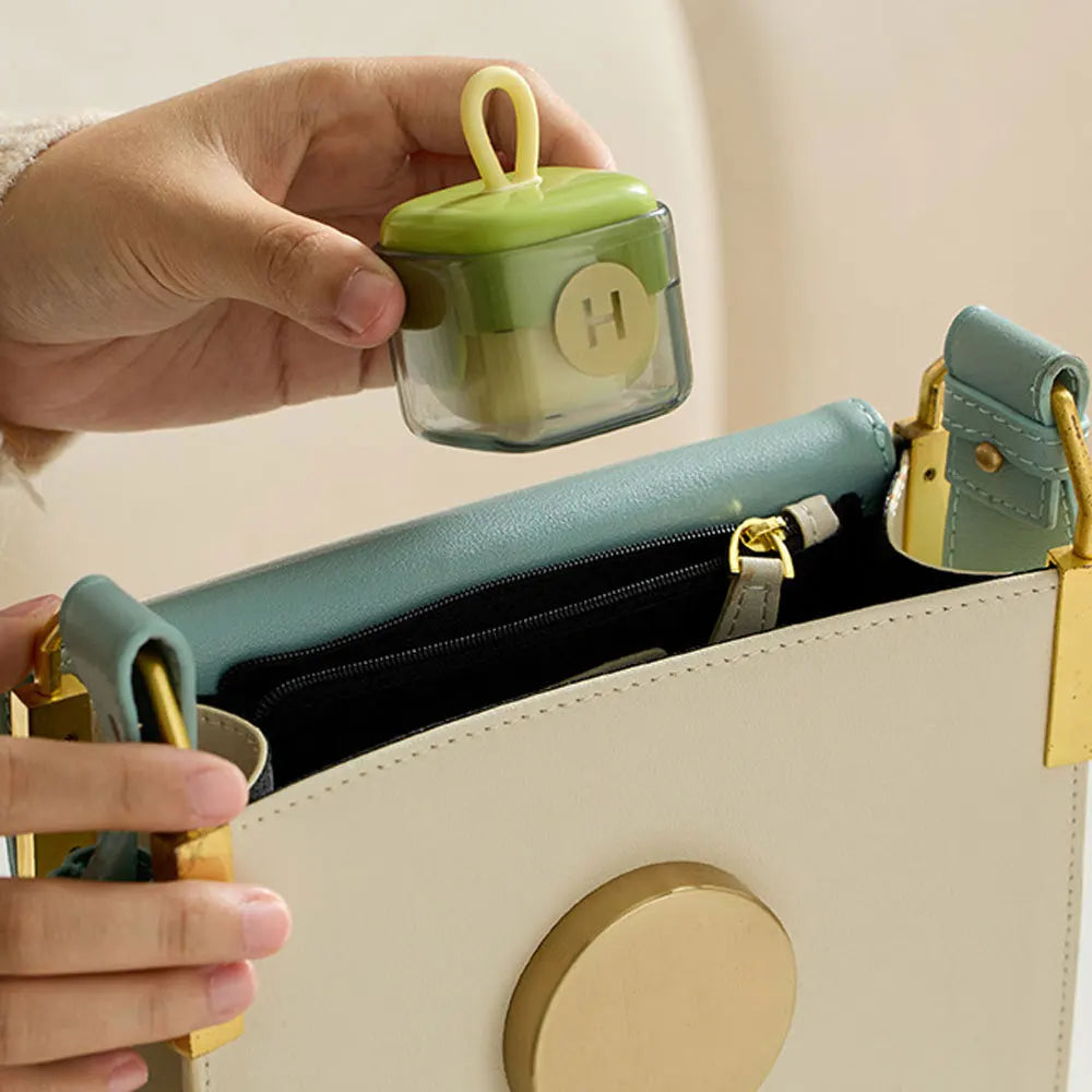 Person holding a small green Lint remover container with a yellow lid over an open beige handbag.